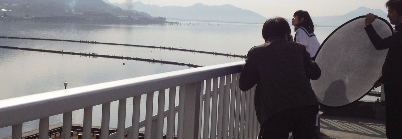 写真：海を見ている女子高生を撮るカメラマンの様子
